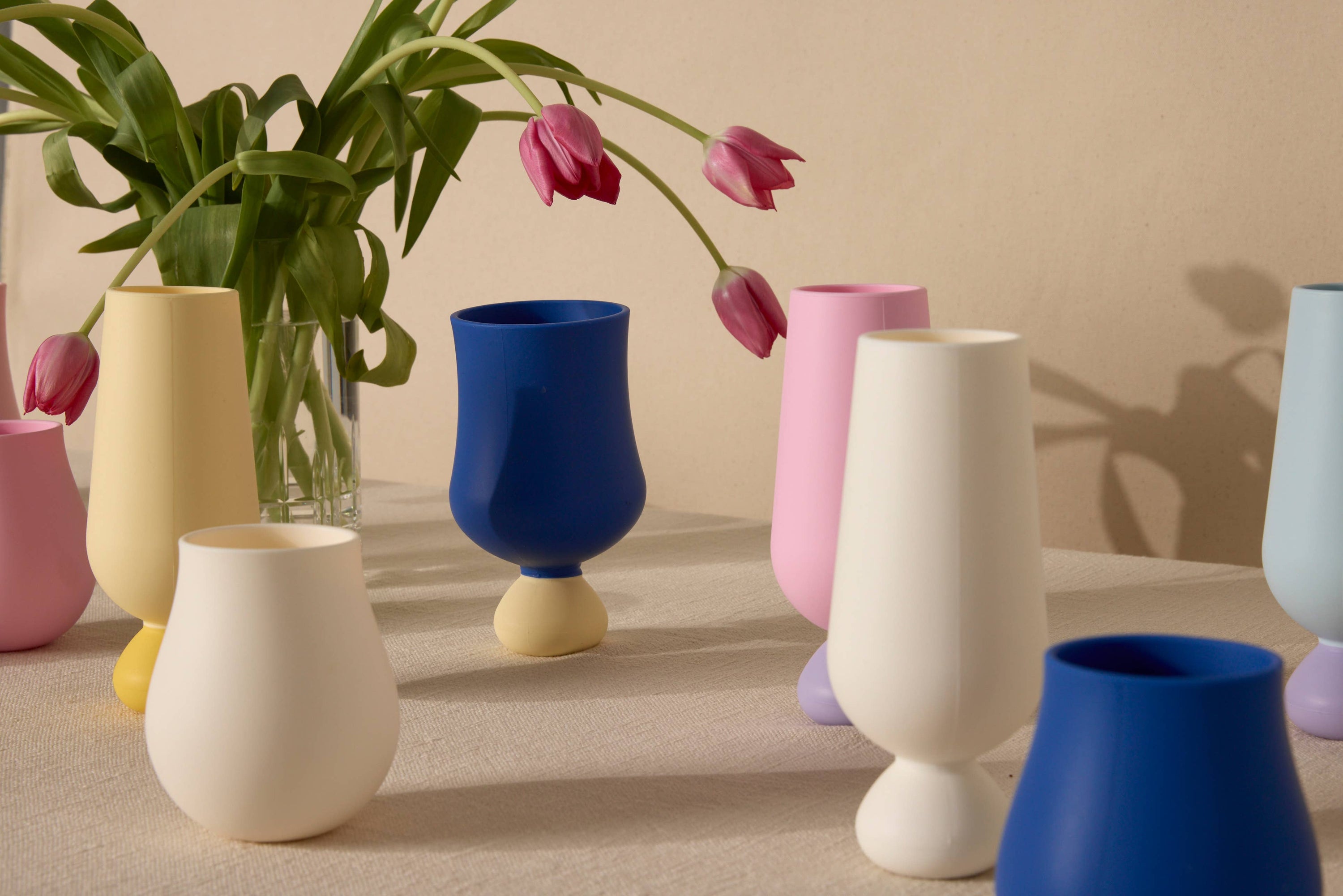 Colorful cups on a neutral surface with a beige wall background