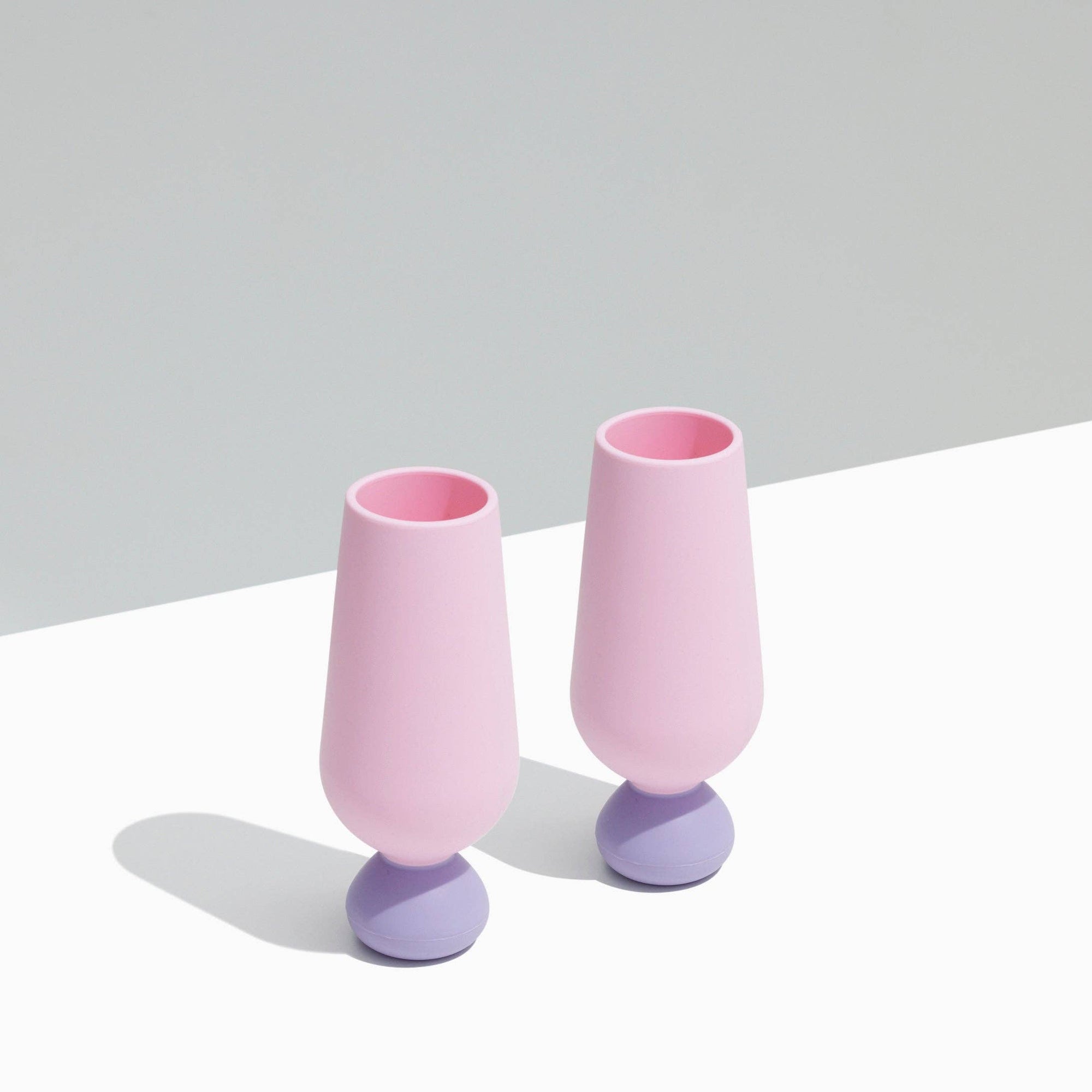 Two pink and purple styld silicone champagne flutes on a light gray background