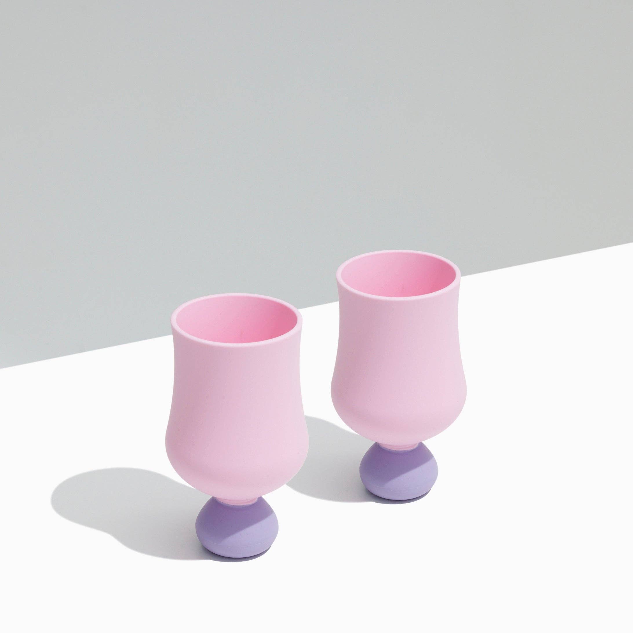 Two pink and purple silicone glasses on a light gray background