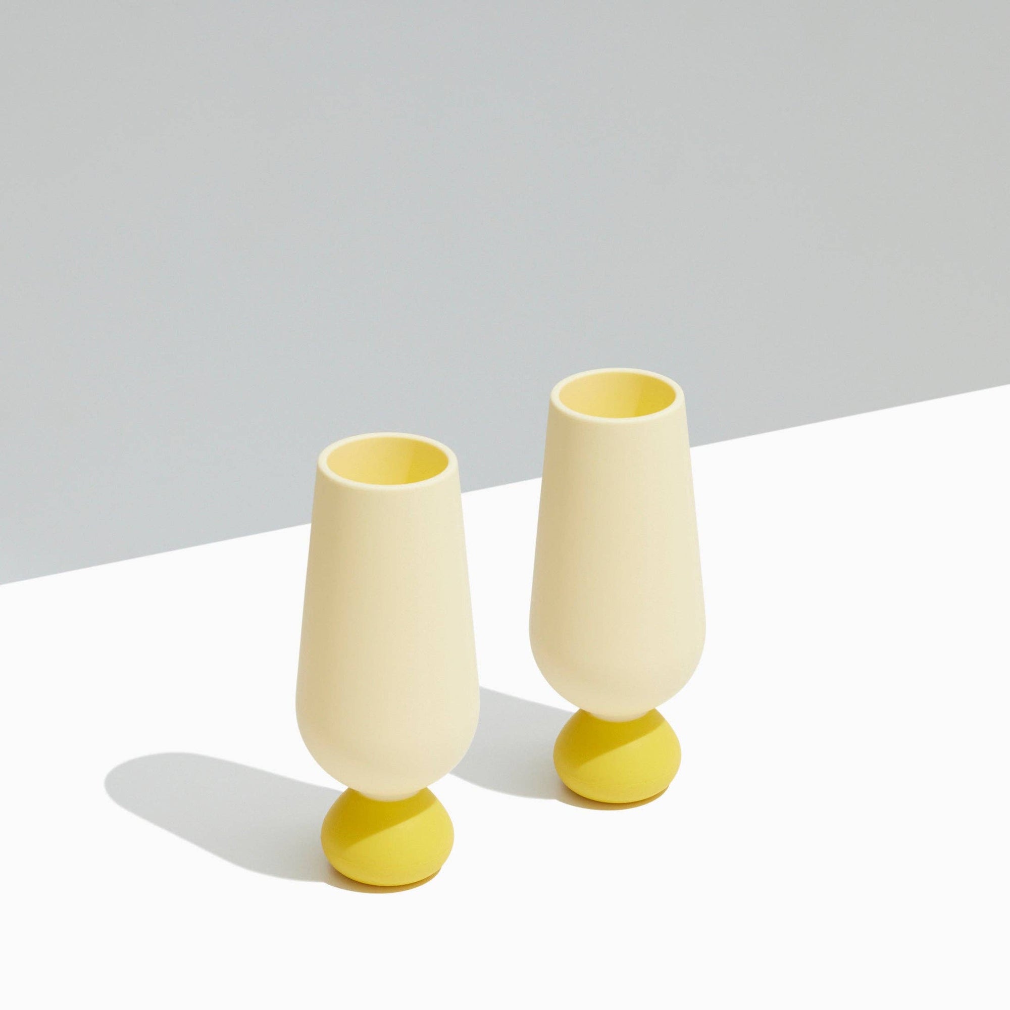 Two yellow and beige silicone champagne cups on a light gray background