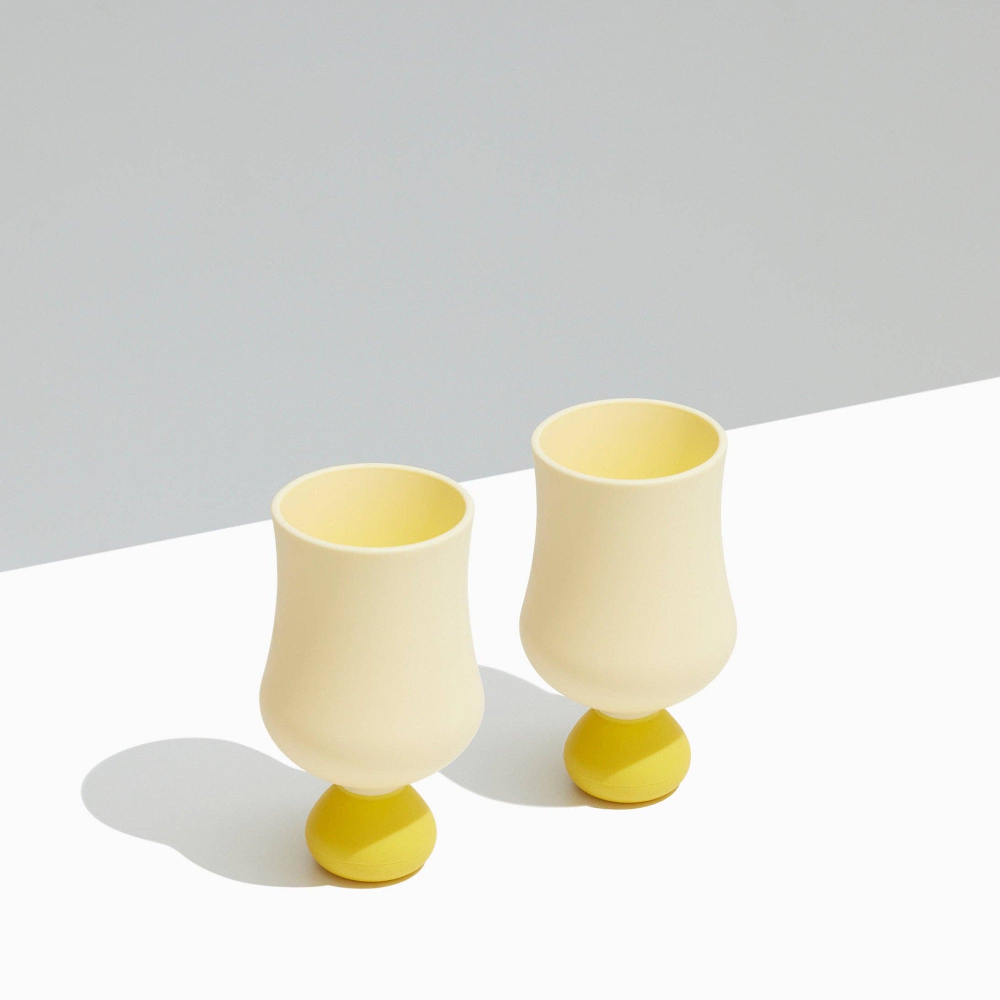 Two yellow silicone cups on a white surface with a light gray background