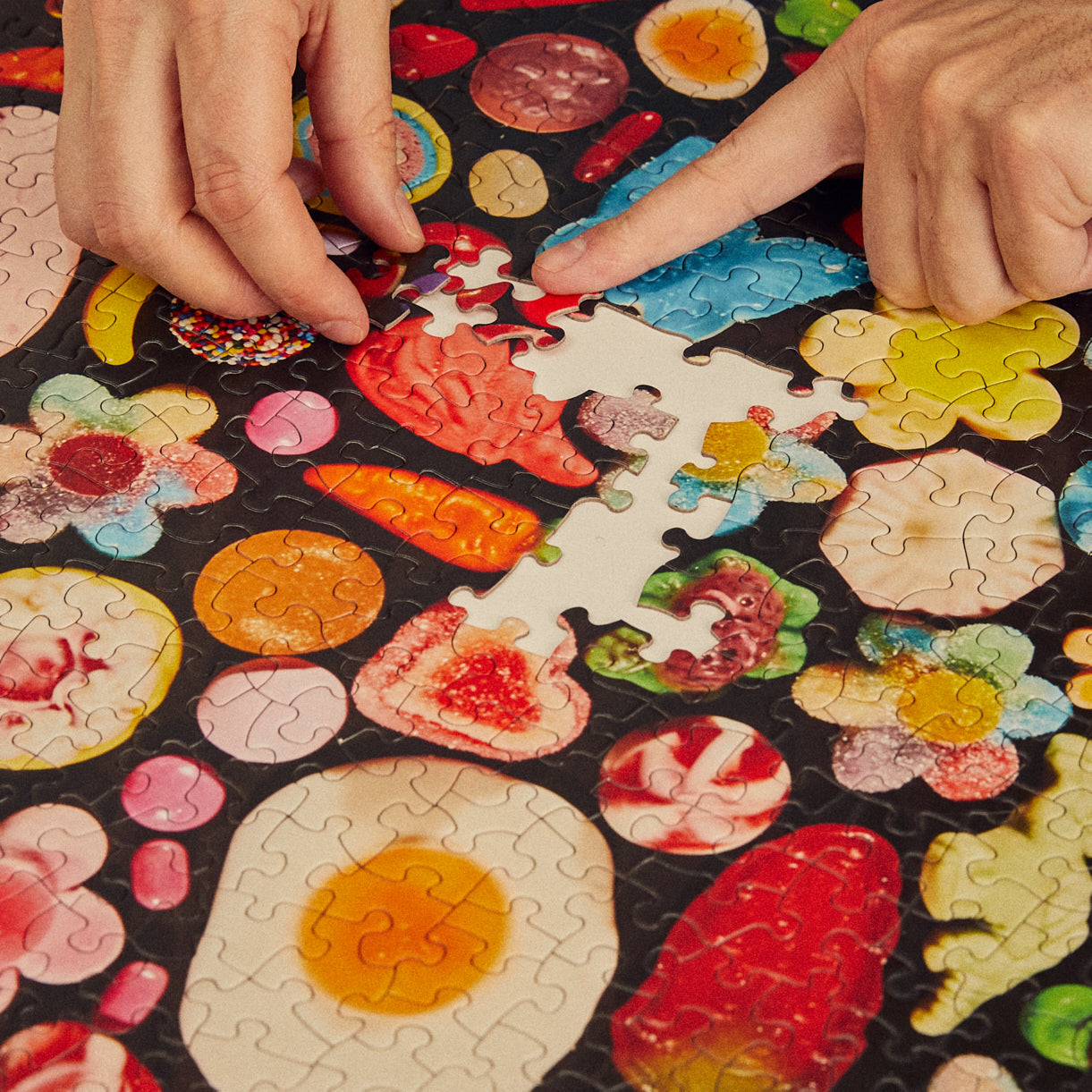 Colorful puzzle with hands trying to fit a piece into place