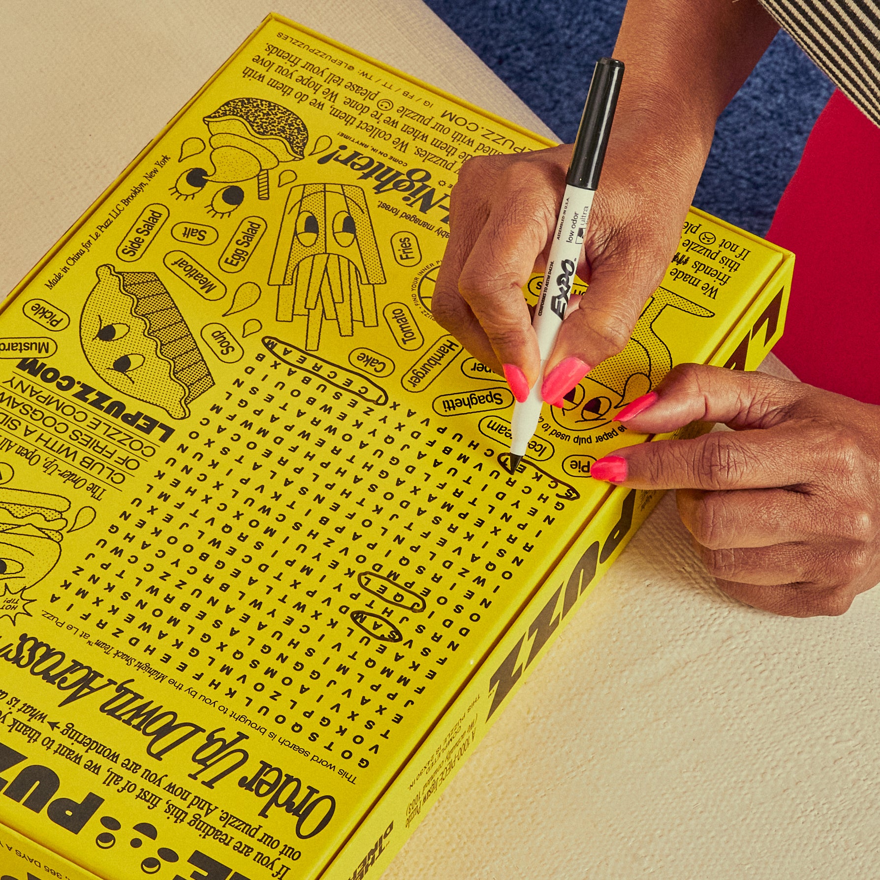 Person writing on the back of a yellow box with a marker le puzz the diner