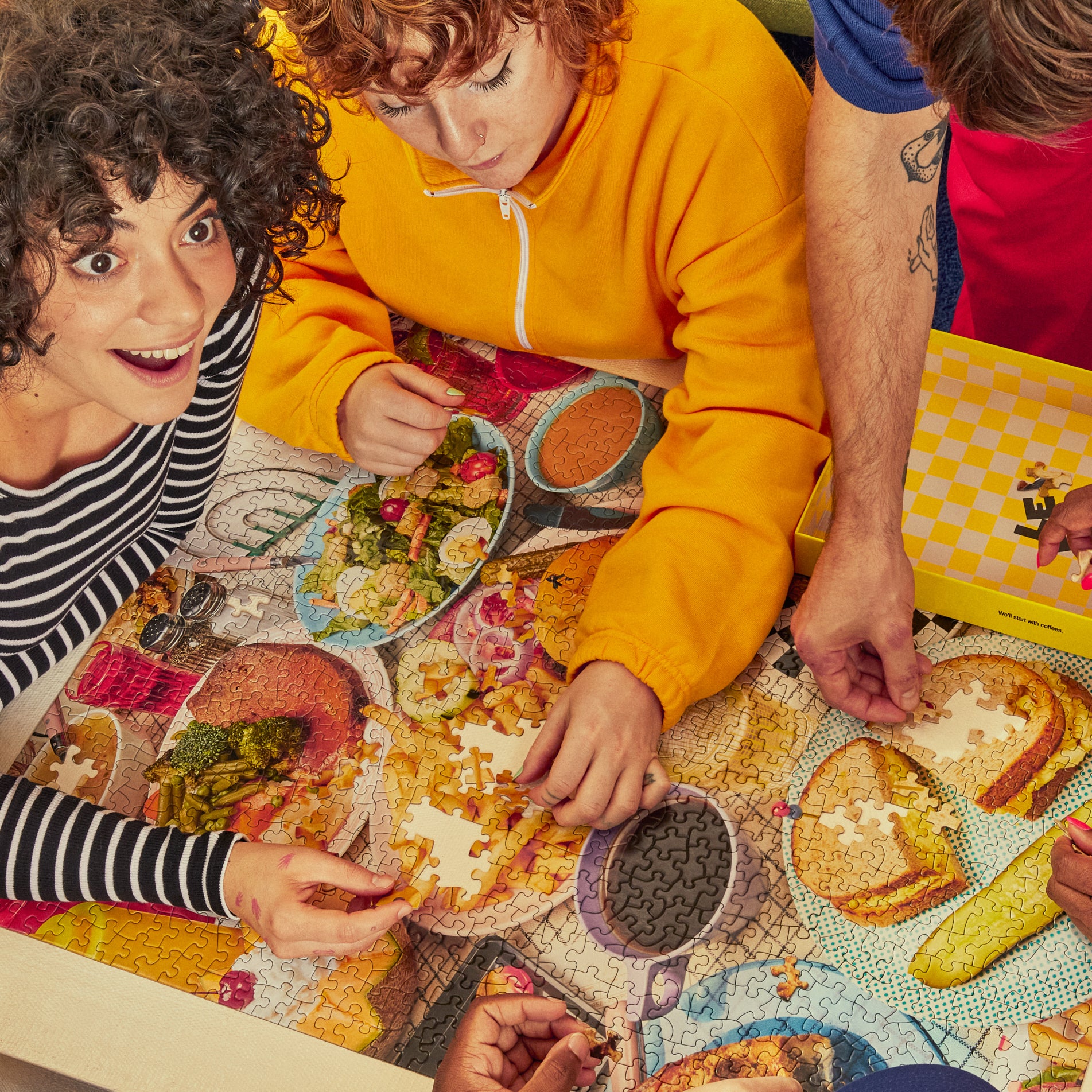 Three people sitting around a table with a colorful tablecloth, engaged in a diner 1000 piece le puzz jigsaw puzzle