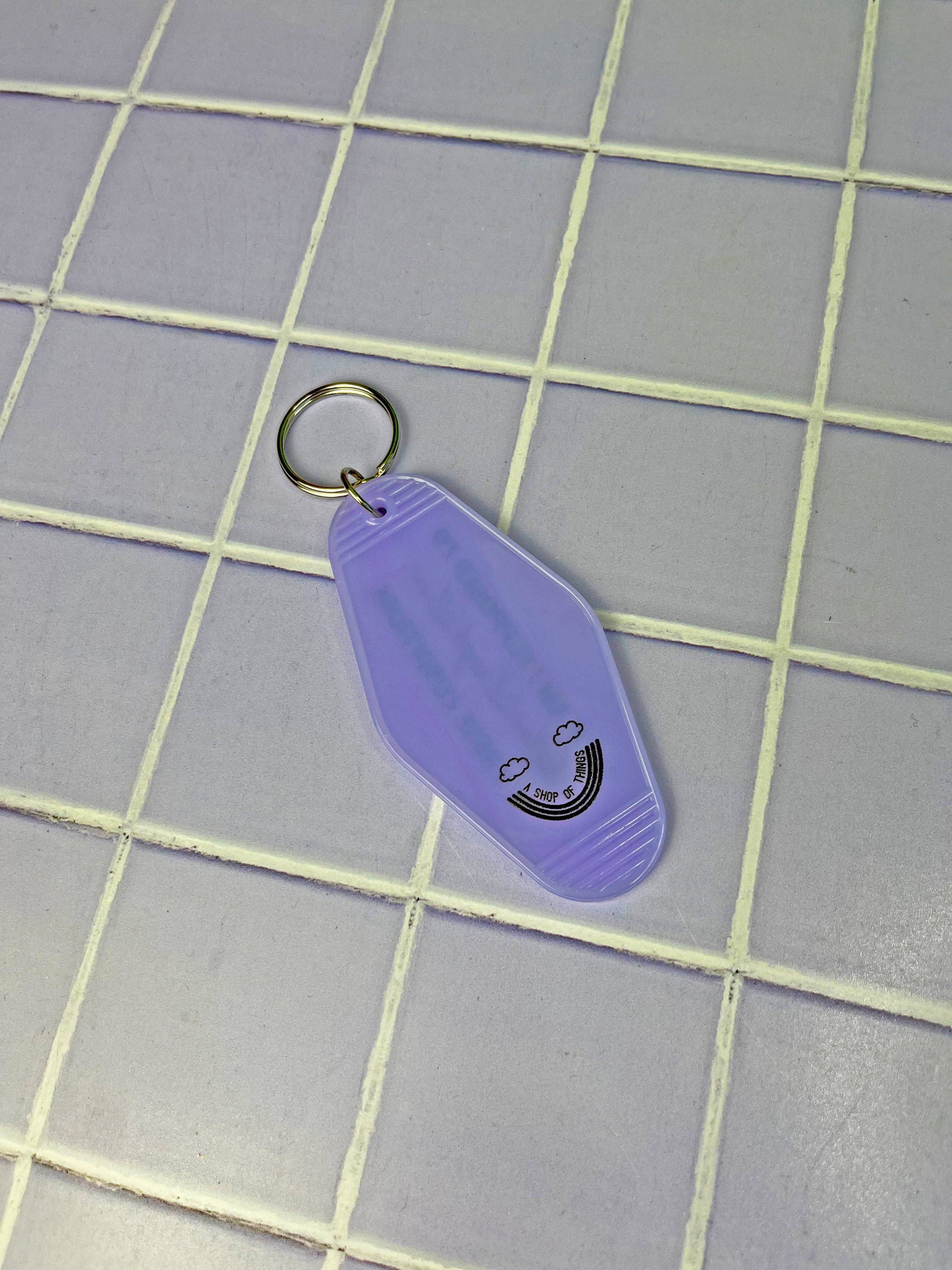 Purple keychain with a smiley face design on a tiled floor