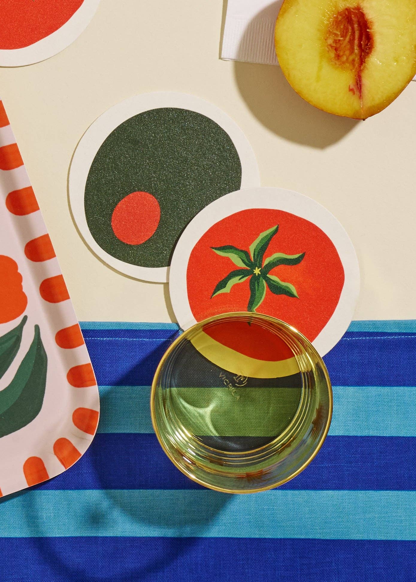 Colorful coasters with fruit designs on a blue and white striped surface.