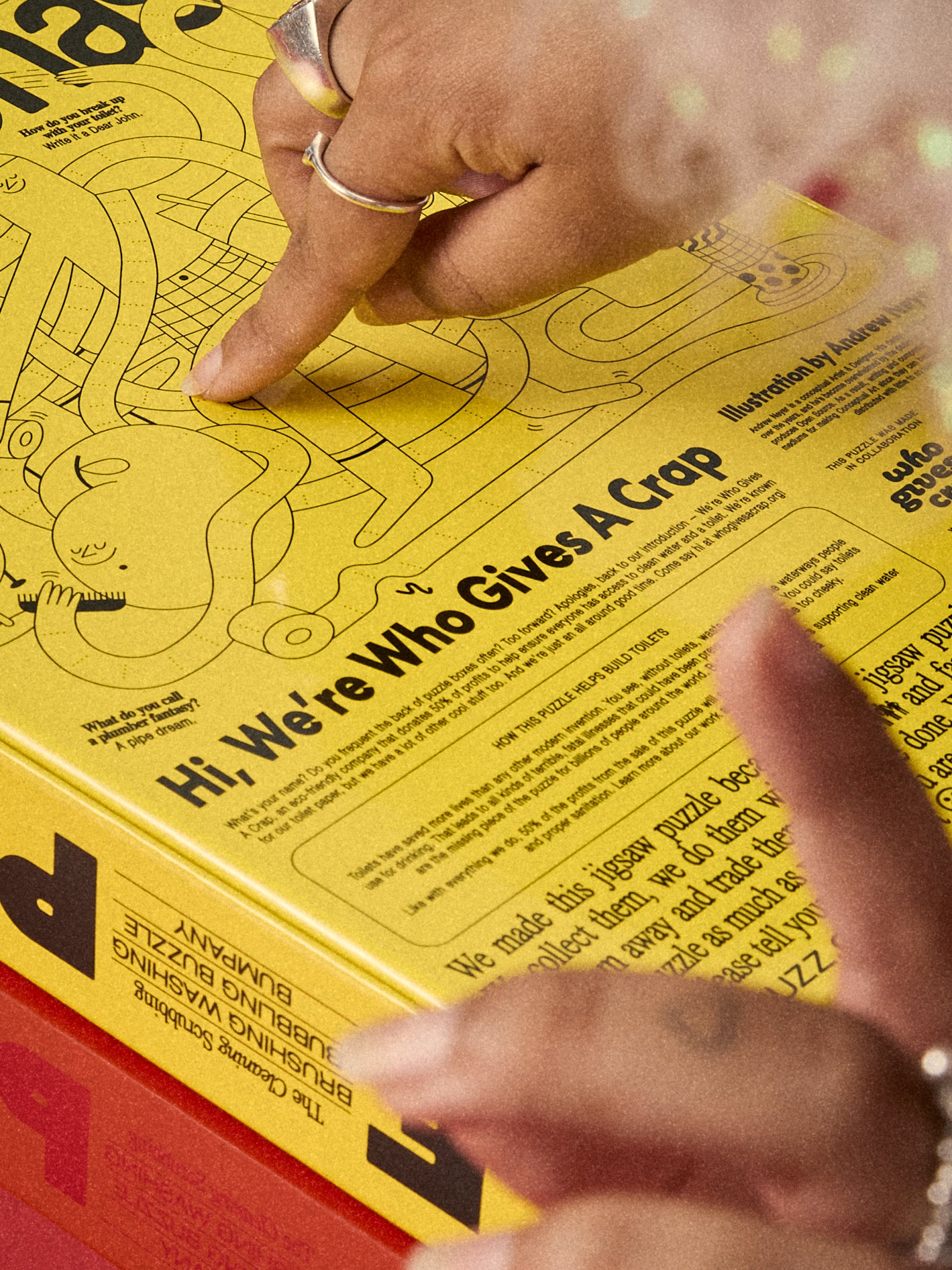 Hands reading the back of the Le Puzz Too-Da-Loo puzzle box featuring Who Gives A Crap collaboration text