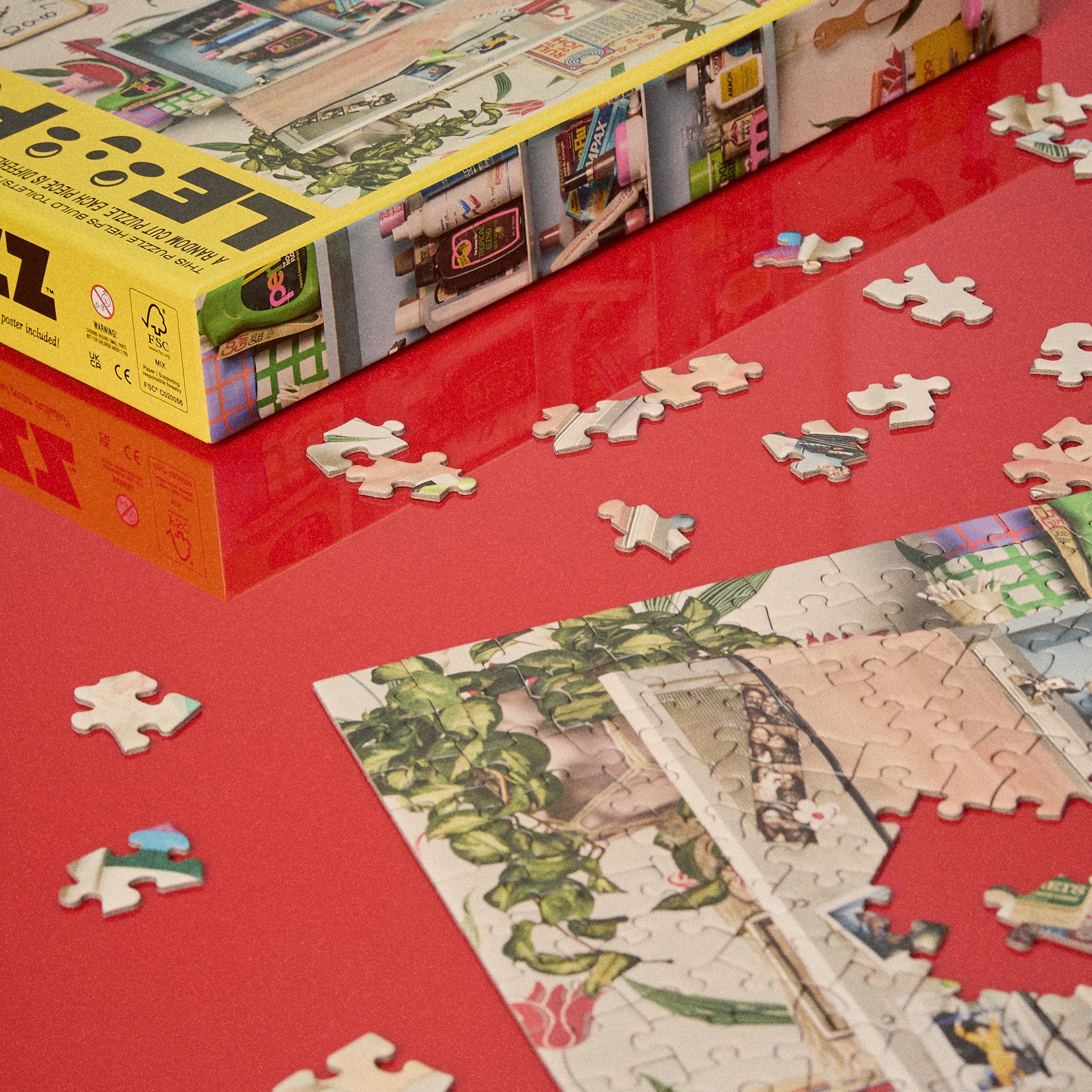 Le Puzz Too-Da-Loo 500 piece puzzle box and scattered pieces on a glossy red surface