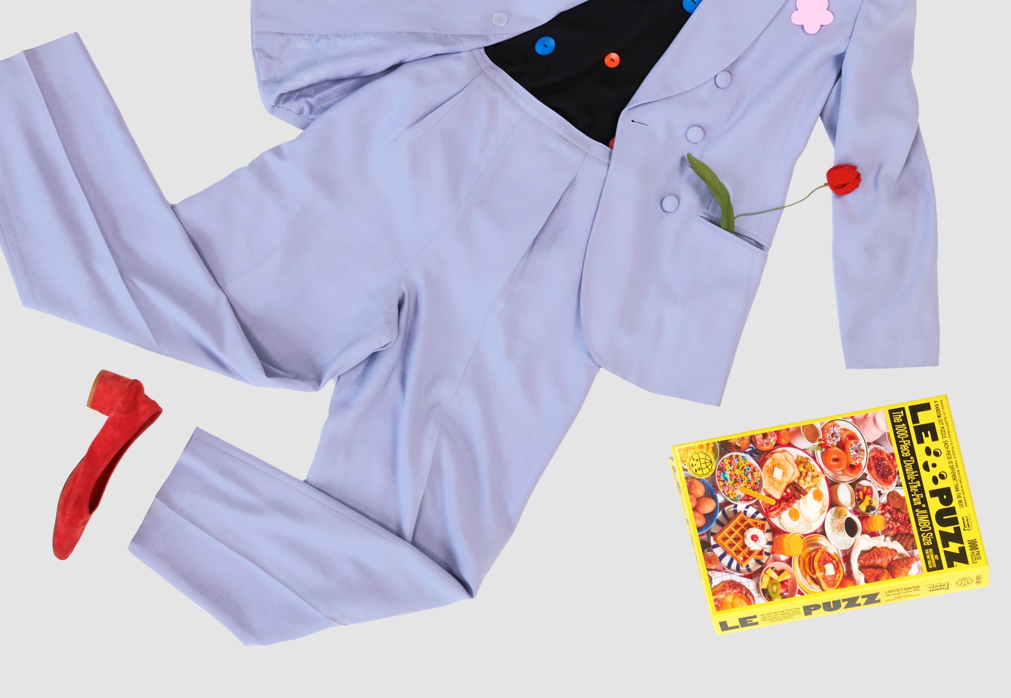 Le Puzz Wakey Wakey puzzle box styled with a powder blue suit, red heels, and cherry brooch on a white background