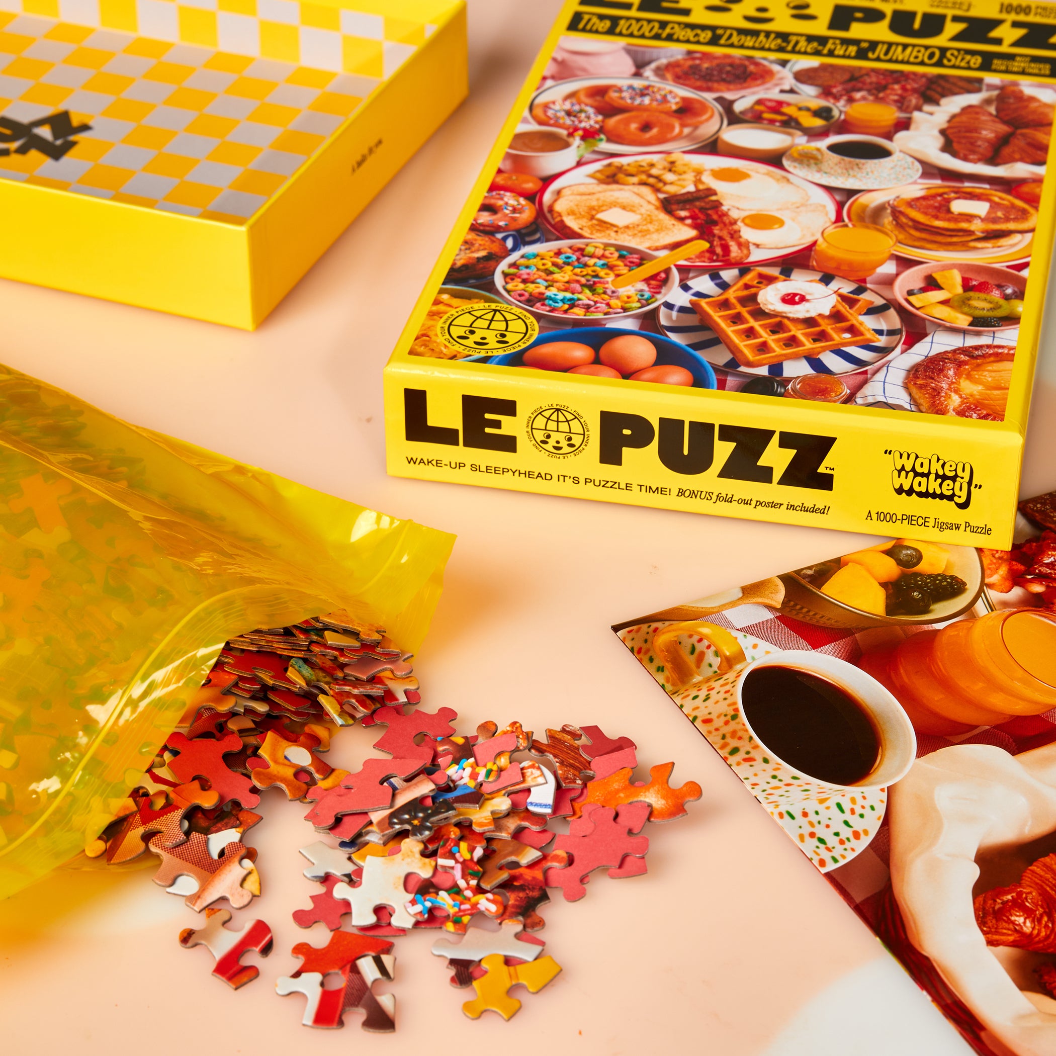 Le Puzz Wakey Wakey 1000-piece puzzle box open with pieces spilling from the yellow resealable bag onto a white surface