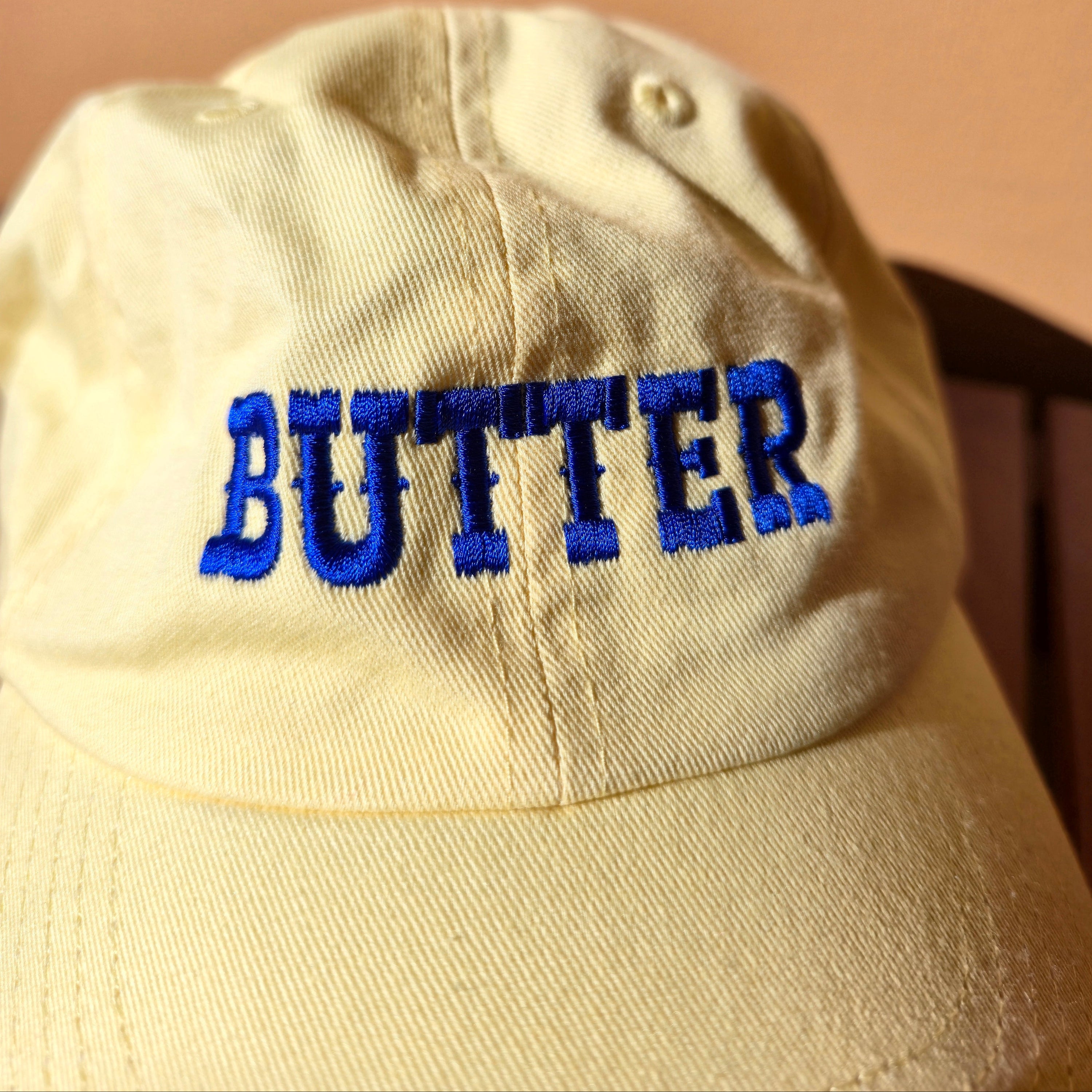 yellow cap with blue 'BUTTER' text on a beige background